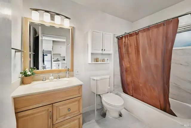 a bathroom with a sink a toilet a mirror and shower curtain