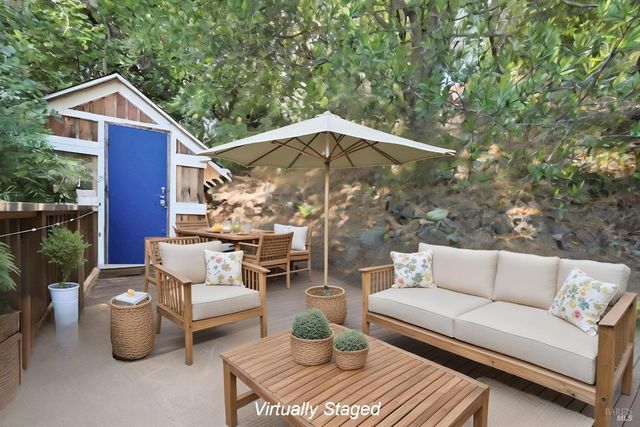 a view of a patio with couches table and chairs under an umbrella