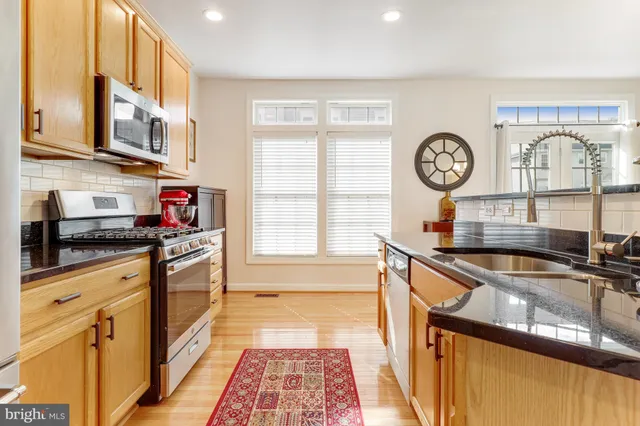 a kitchen with stainless steel appliances granite countertop a refrigerator a stove and a sink