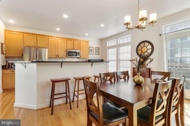 a kitchen with stainless steel appliances kitchen island granite countertop a stove a refrigerator a kitchen island a stove a dining table and chairs with wooden floor