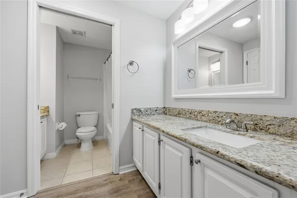 a bathroom with a granite countertop sink a toilet and a mirror