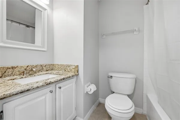 a bathroom with a granite countertop toilet and a sink