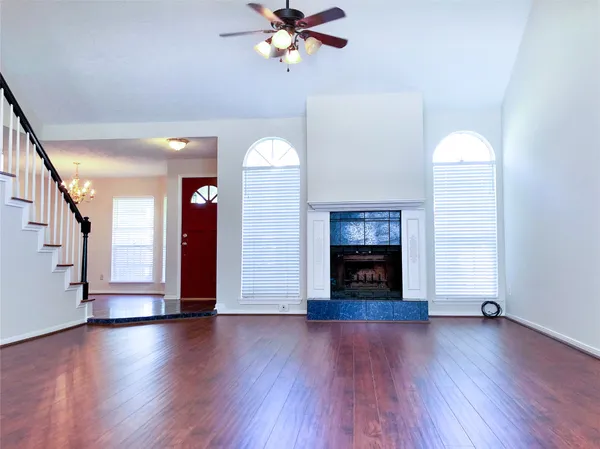 a view of an empty room with wooden floor fireplace and a window