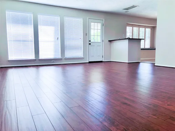 an empty room with wooden floor and windows