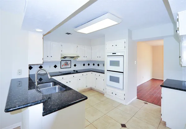 a large kitchen with stainless steel appliances granite countertop a sink stove and white cabinets