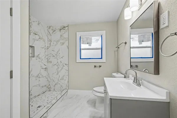 a bathroom with a sink a toilet and shower