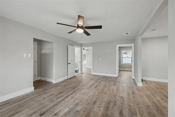 a view of empty room with wooden floor and ceiling fan