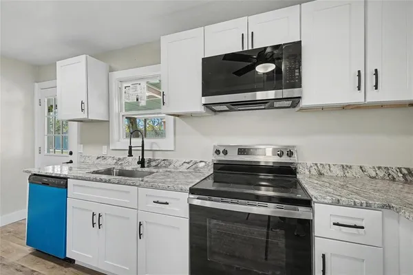 a kitchen with stainless steel appliances granite countertop white cabinets granite counter tops and a wooden floors