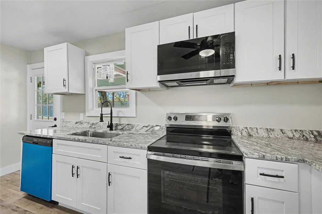 4220 Ramey Avenue Fort Worth, TX 76105 - Photo 10 of 24 a kitchen with stainless steel appliances granite countertop white cabinets granite counter tops and a wooden floors