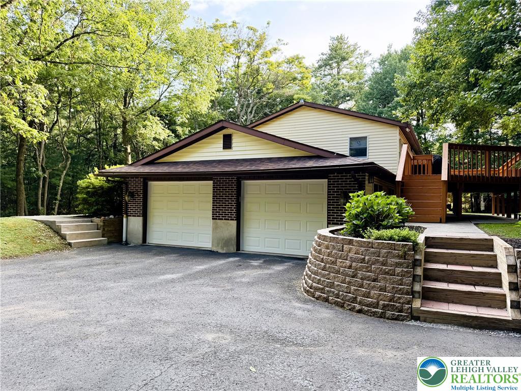 525 Pinewood Road Lehighton, PA 18235 - Photo 35 of 51 A spacious driveway leads to an attached two-car garage, complemented by mature trees and terraced landscaping.