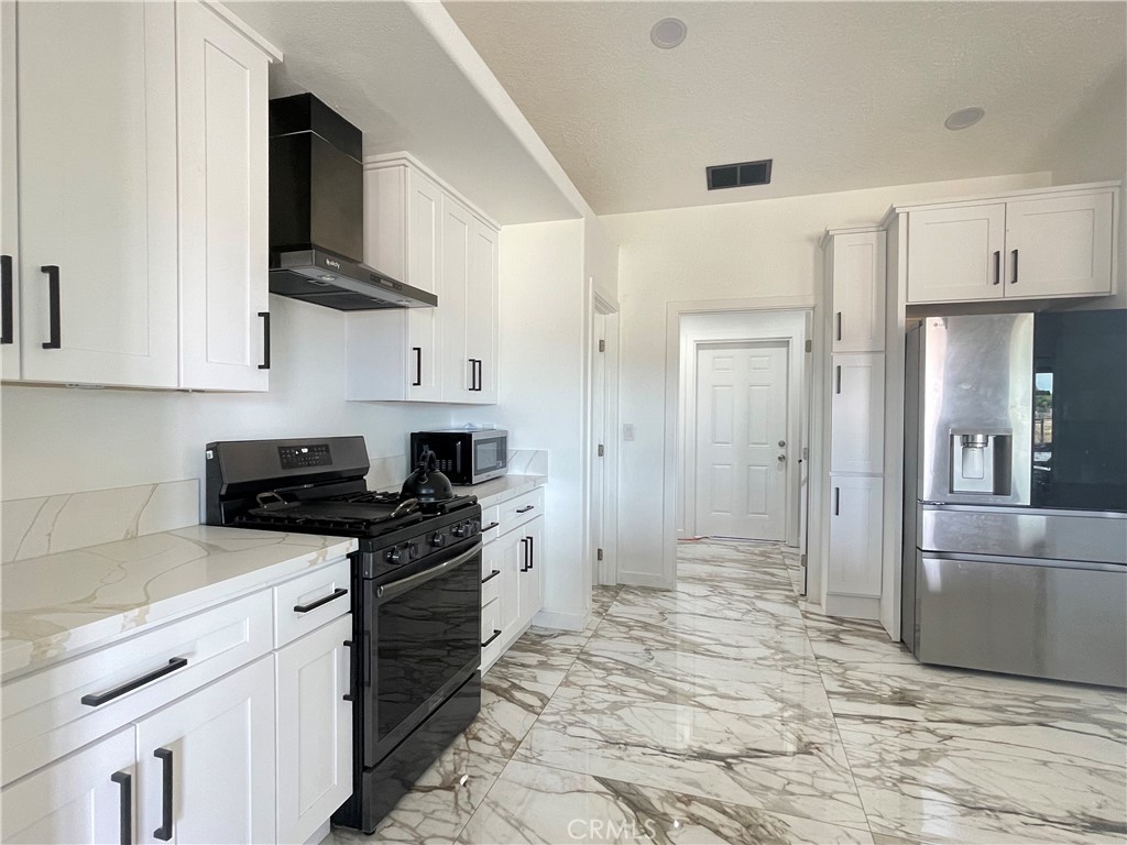 11375 4th Hesperia, CA 92345 - Photo 29 of 37 a kitchen with stainless steel appliances granite countertop a stove a refrigerator and a white cabinets