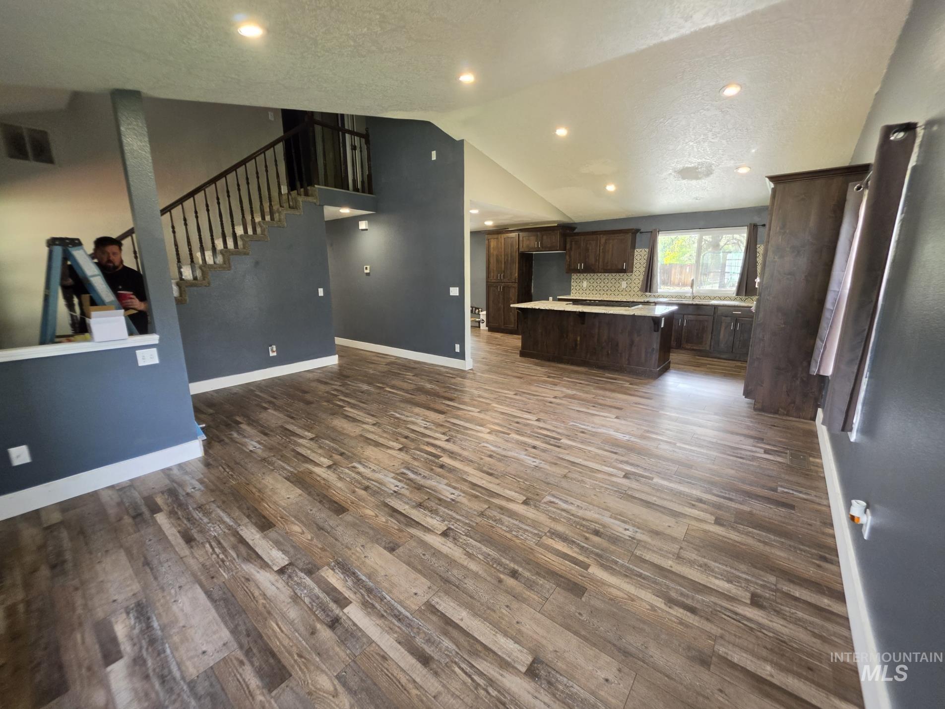 3201 South Riva Ridge Way Boise City, ID 83709 - Photo 9 of 29 Wood-finish flooring throughout, vaulted ceiling, recessed lighting, dark wood cabinetry, and a kitchen island with built-in cooktop