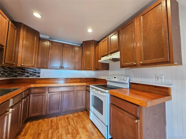 a kitchen with stainless steel appliances granite countertop wooden cabinets a sink and dishwasher a stove with wooden floor