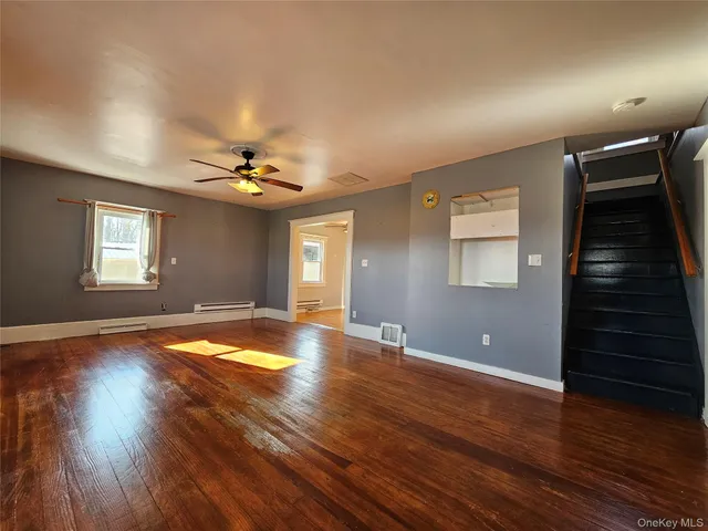 a view of a livingroom with wooden floor and staircase