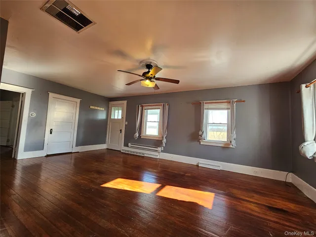 a view of empty room with wooden floor and fan