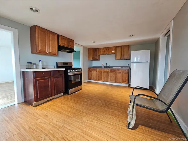 a kitchen with stainless steel appliances granite countertop a stove top oven a sink dishwasher and wooden cabinets with wooden floor