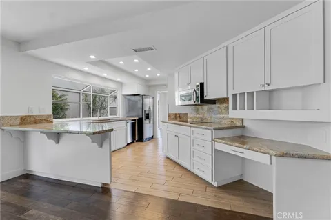 a kitchen with stainless steel appliances granite countertop a stove top oven a sink a counter space and cabinets