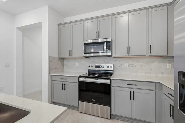 a kitchen with granite countertop white cabinets and stainless steel appliances