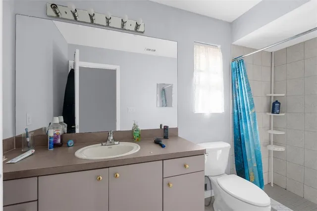 a bathroom with a granite countertop sink toilet and mirror
