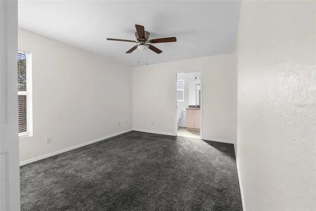 an empty room with a ceiling fan and carpet
