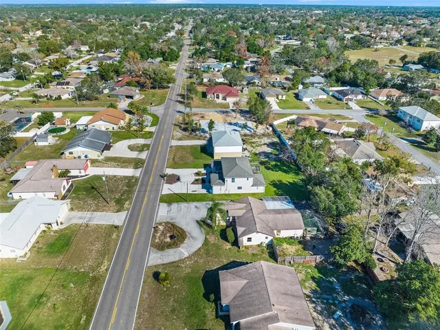 an aerial view of residential houses with outdoor space and trees