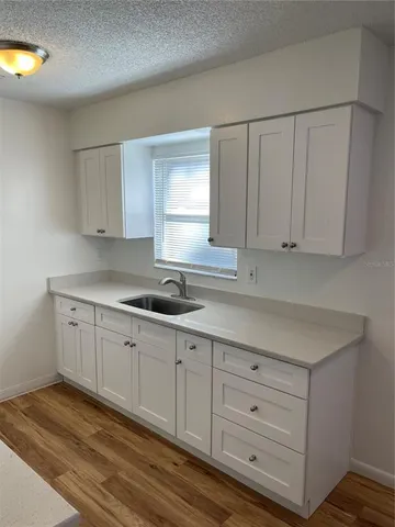 a kitchen with granite countertop white cabinets and sink
