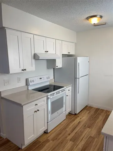 a kitchen with a sink a stove a refrigerator and white cabinets