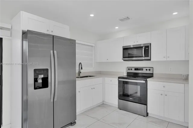 a kitchen with stainless steel appliances granite countertop a refrigerator a stove a sink and a microwave