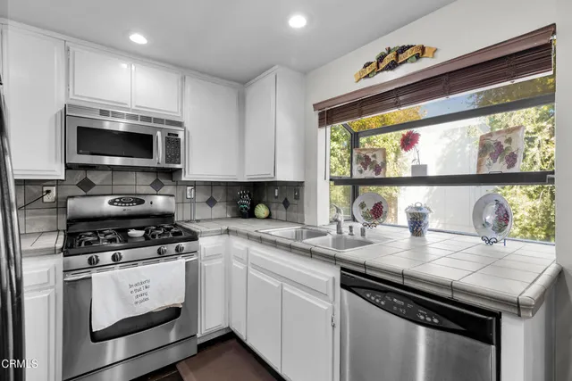 a kitchen with stainless steel appliances granite countertop a stove a sink and a microwave