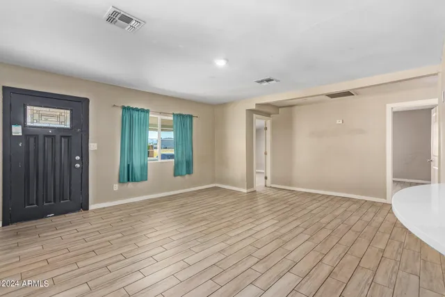 a view of an empty room with wooden floor and a bathroom