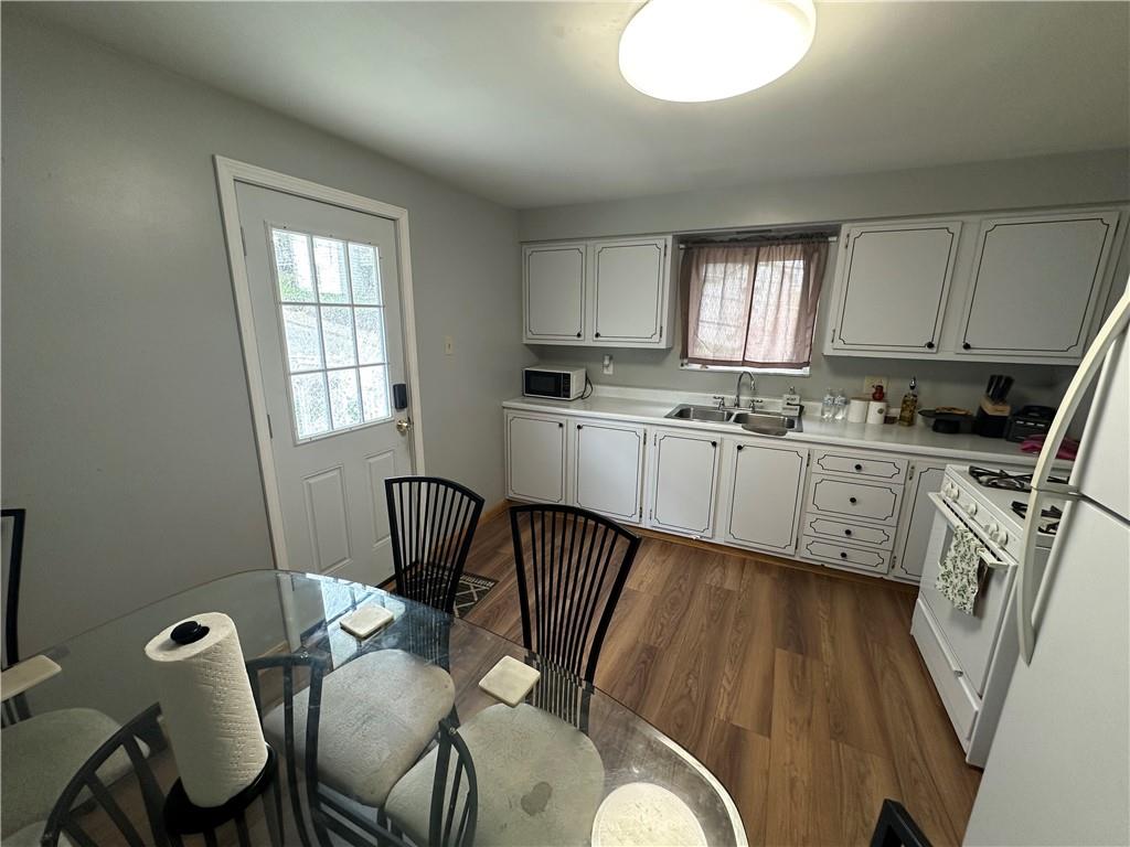 900 State Avenue Coraopolis, PA 15108 - Photo 7 of 19 a kitchen with stainless steel appliances granite countertop a sink a stove a refrigerator a microwave oven with white cabinets and wooden floor