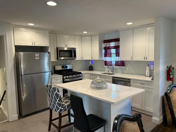 a kitchen with a refrigerator a stove a sink a dining table and chairs