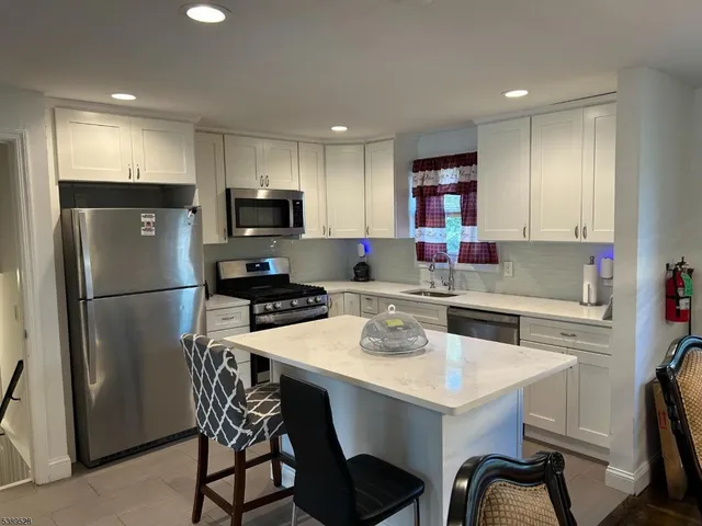 a kitchen with a refrigerator a stove a sink a dining table and chairs