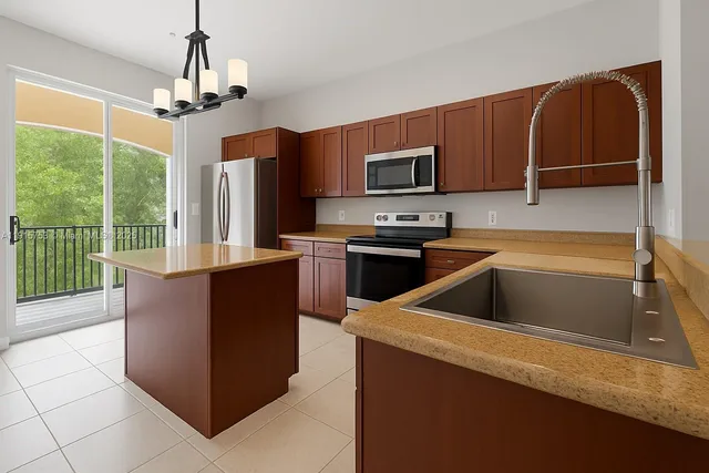 a kitchen with stainless steel appliances granite countertop a refrigerator a sink a stove top oven a counter space and cabinets