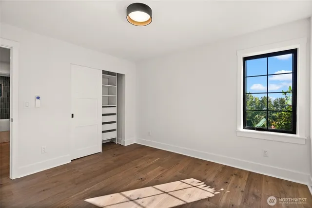 an empty room with wooden floor cabinet and windows