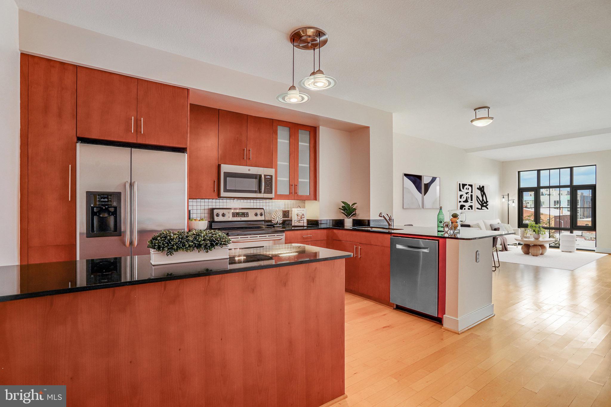 910 M Street Northwest, Unit 516 Washington, DC 20001 - Photo 4 of 29 a large kitchen with stainless steel appliances granite countertop a refrigerator a sink dishwasher a stove with wooden cabinets and floor