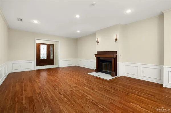 a view of an empty room with wooden floor fireplace and a window