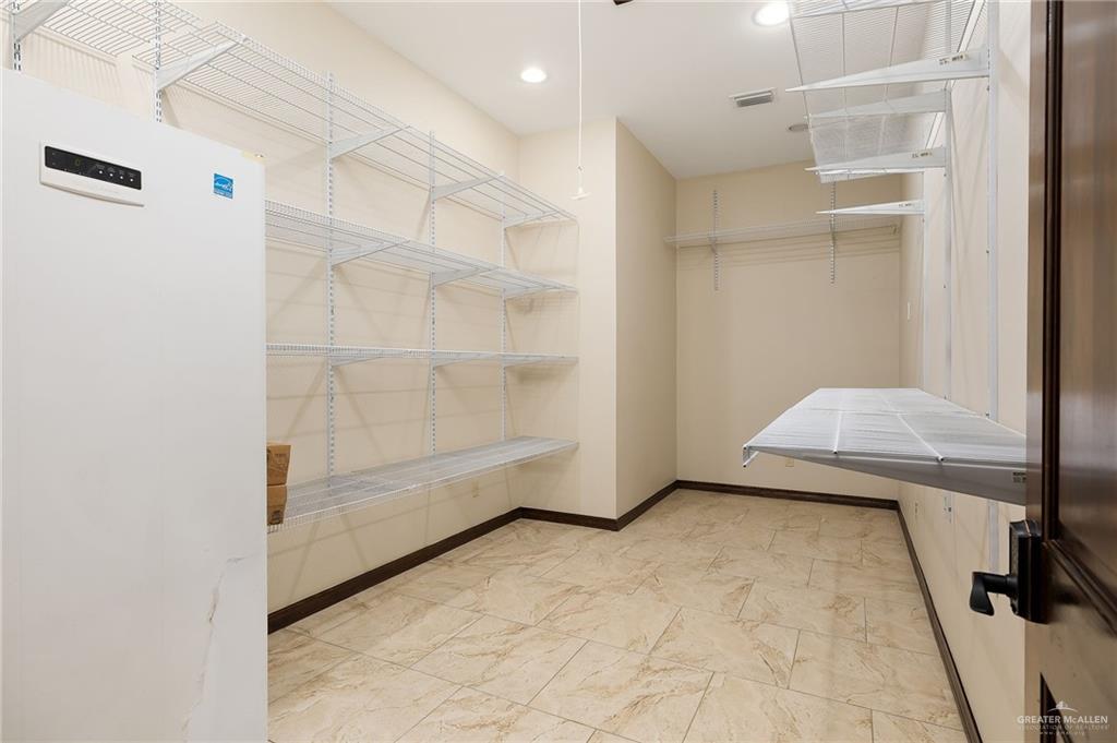 4725 Mile 6 Road McAllen, TX 78504 - Photo 44 of 45 Climate controlled storage room with a shelving system for holiday/everyday storage, attic access, up right freezer and a light switched that controls exterior soffit outlets for holiday lights.