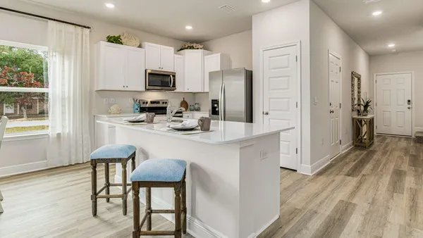 a kitchen with stainless steel appliances granite countertop a refrigerator a stove microwave and white cabinets with wooden floor