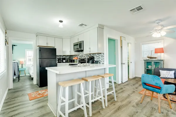 a kitchen with stainless steel appliances kitchen island granite countertop a refrigerator a stove top oven and a dining table with wooden floor
