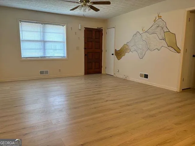 an empty room with wooden floor and windows