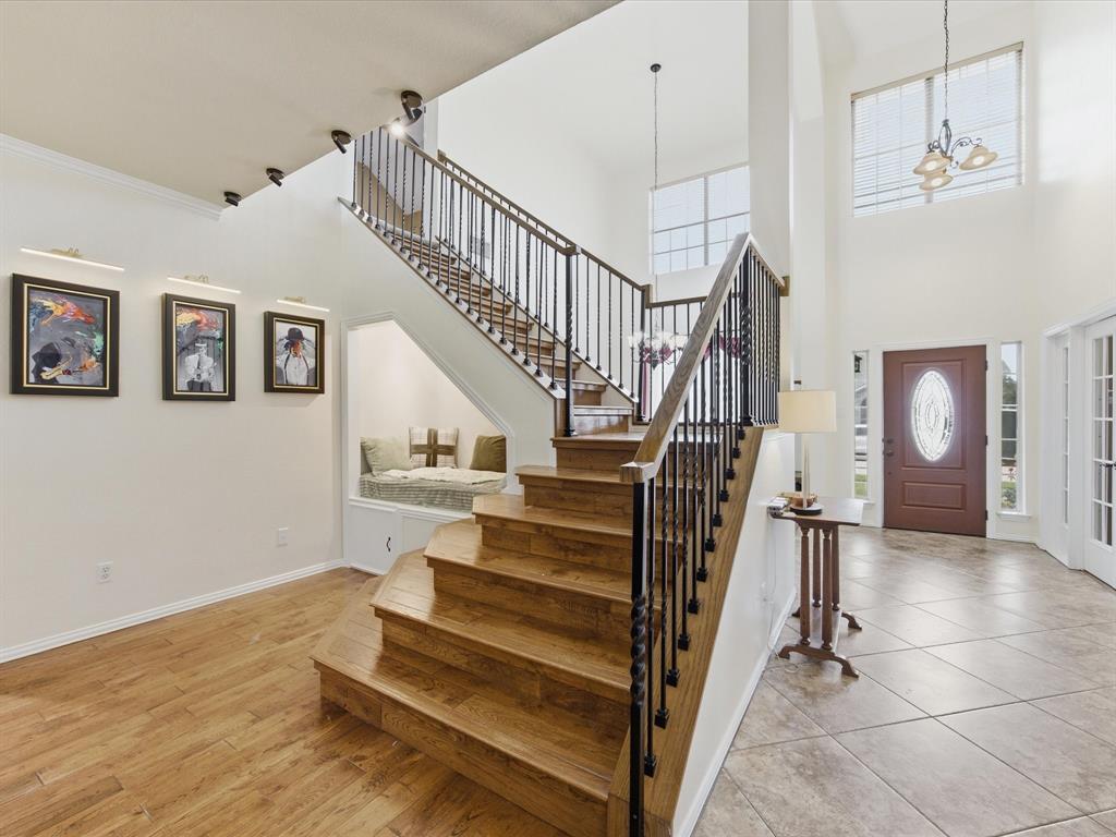 4008 Falcon Ridge Drive Haltom City, TX 76137 - Photo 9 of 40 Two-story foyer featuring wood-finish flooring, a grand staircase with wrought iron balusters, a built-in window seat, a decorative front door with an oval glass insert, and high ceilings with upper-level windows
