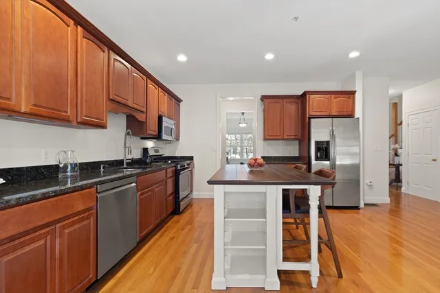 a kitchen with stainless steel appliances granite countertop wooden cabinets a sink and dishwasher a stove top oven with wooden floor