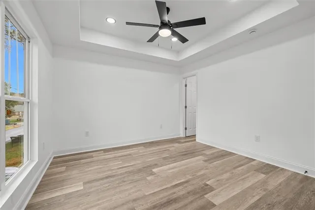 an empty room with wooden floor and a ceiling fan