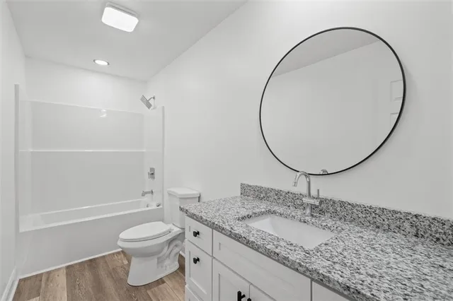 a bathroom with a granite countertop sink a toilet and a mirror