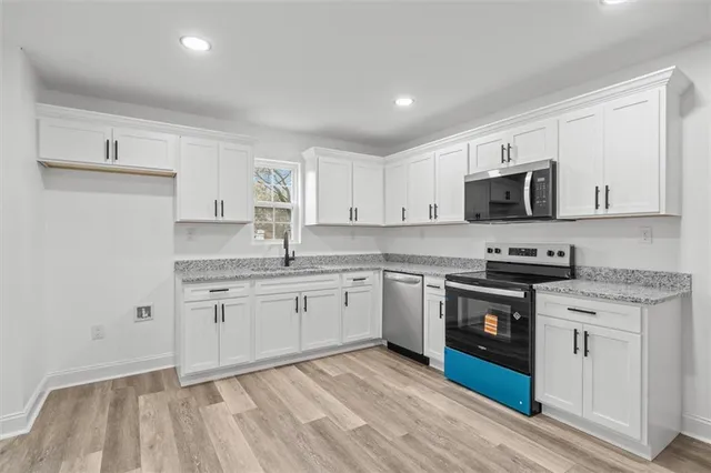 a kitchen with granite countertop a sink stove and microwave
