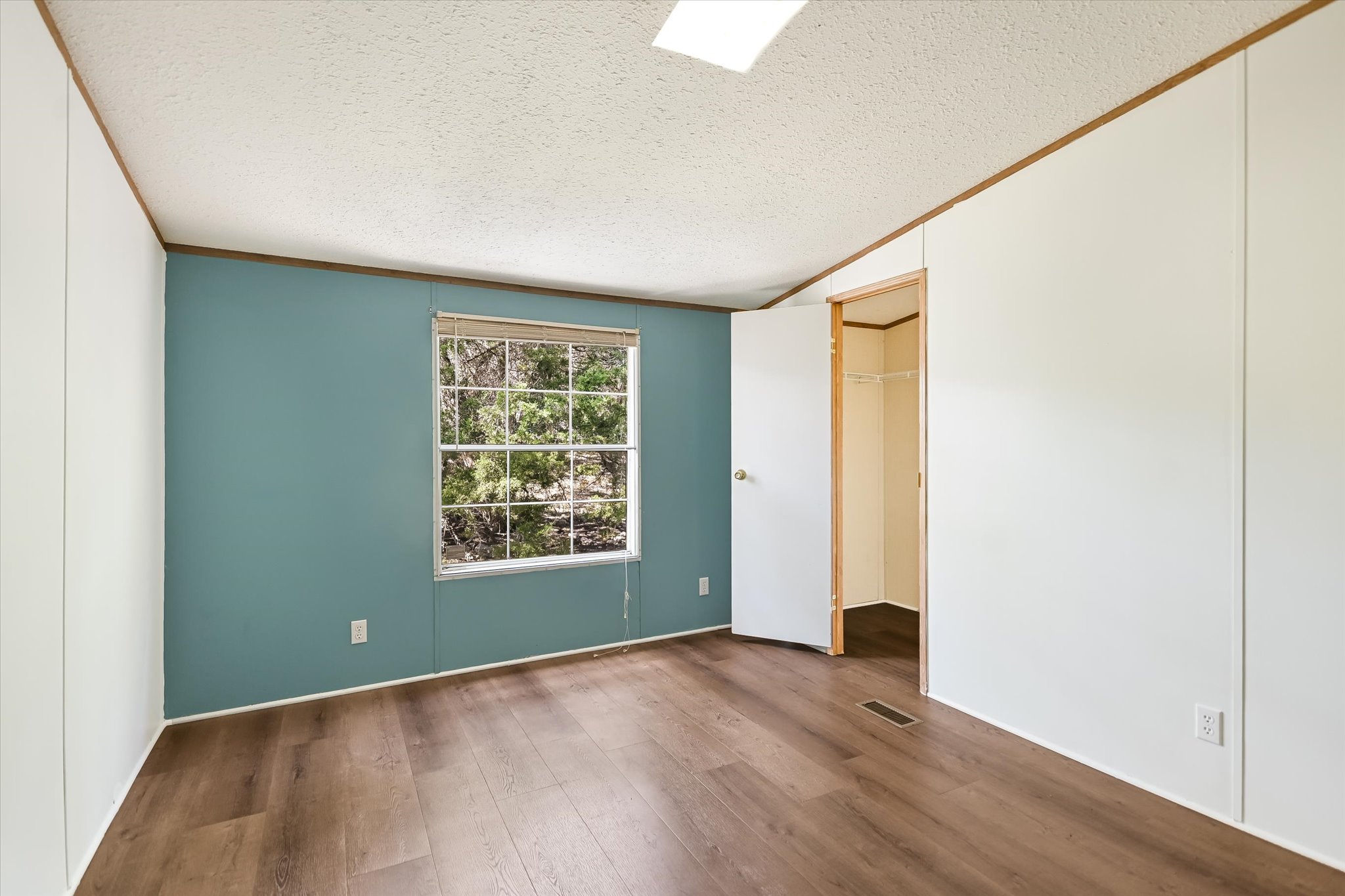 217 Rousey Street Canyon Lake, TX 78133 - Photo 21 of 25 a view of an empty room with wooden floor and a window