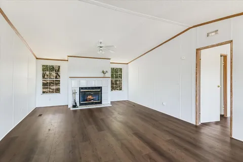 a view of an empty room with wooden floor fireplace and a window
