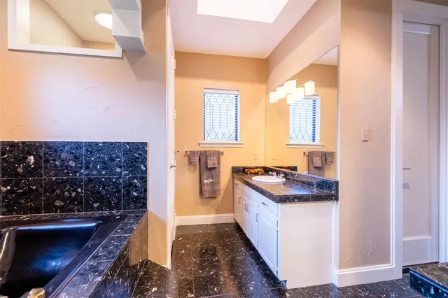 a bathroom with a granite countertop sink a mirror and a bathtub