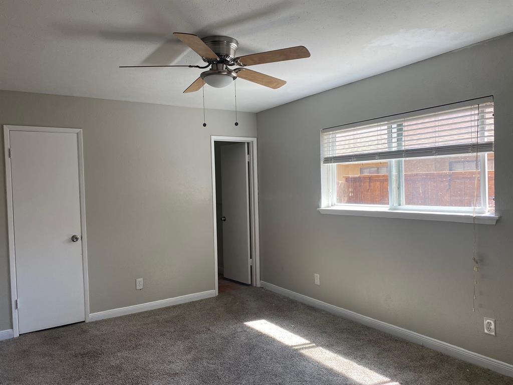 1109 Cross Bend Road Plano, TX 75023 - Photo 9 of 11 Carpeted interior room with neutral-toned walls, featuring a window with horizontal blinds, a ceiling fan with integrated lighting, and two white interior doors